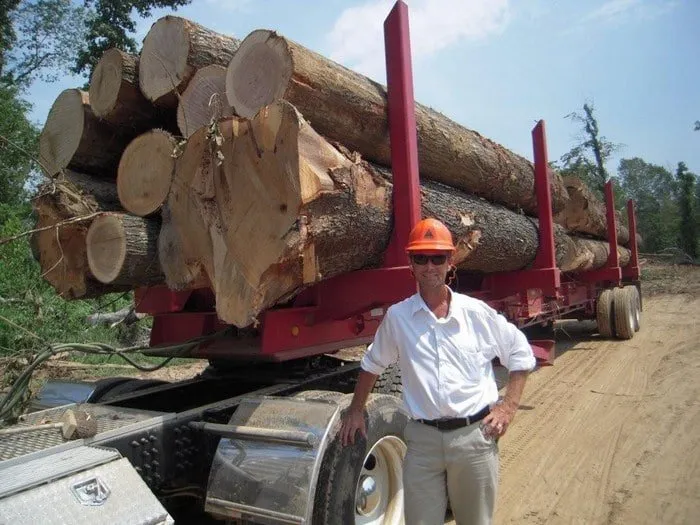 Greg Hooper standing in front of a trailer loaded with large logs